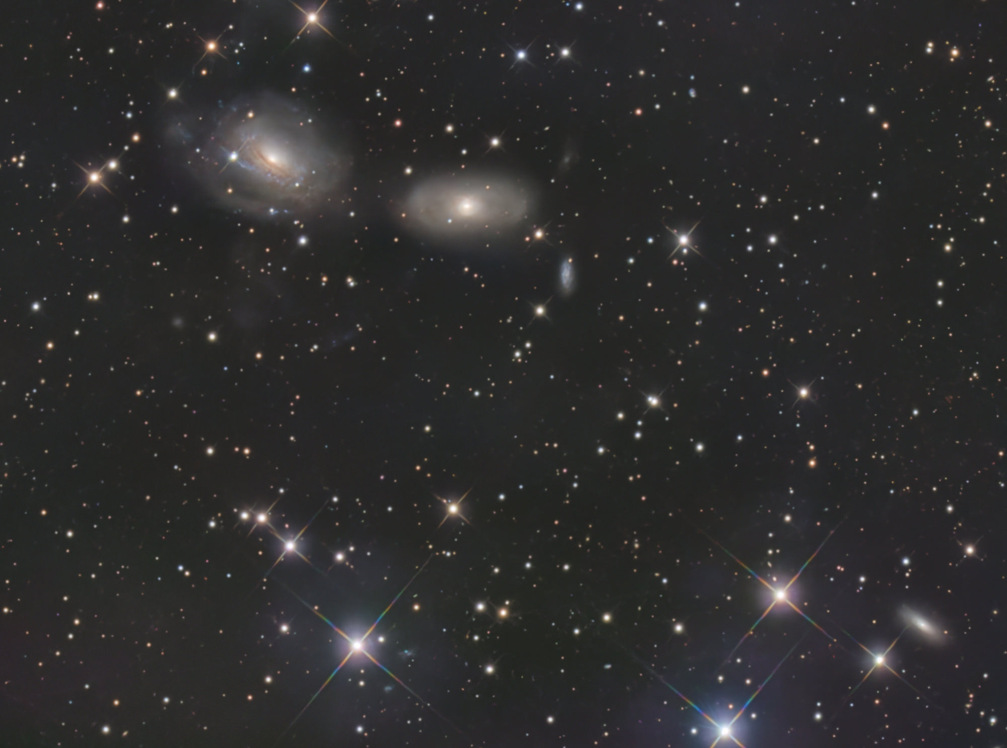 The twisting spiral arms of NGC 3169 (left) have been pulled out into sweeping tidal tails by gravitational interaction with the neighboring galaxy NGC 3166. The two galaxies will eventually merge into one.